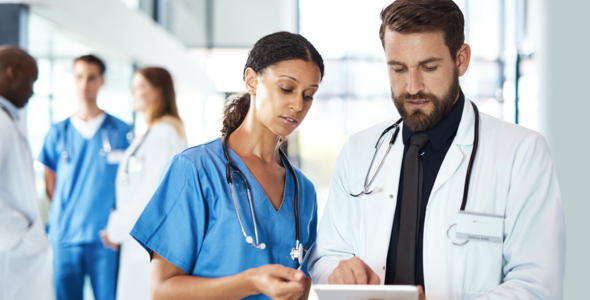 two medical professionals, one male and one female, looking at a chart