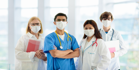 Four doctors standing side by side wearing masks